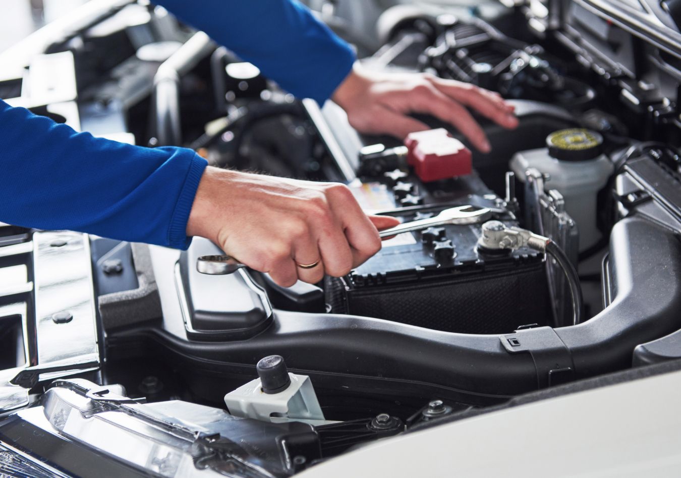 Eine Person hält einen Schlüssel über der Autobatterie